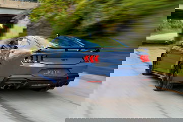 Captura dinámica del Ford Mustang mostrando su musculosa silueta y pilotos traseros icónicos.