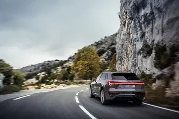Audi Q8 e-tron capturado en plena ruta montañosa, destacando su diseño trasero y lateral.