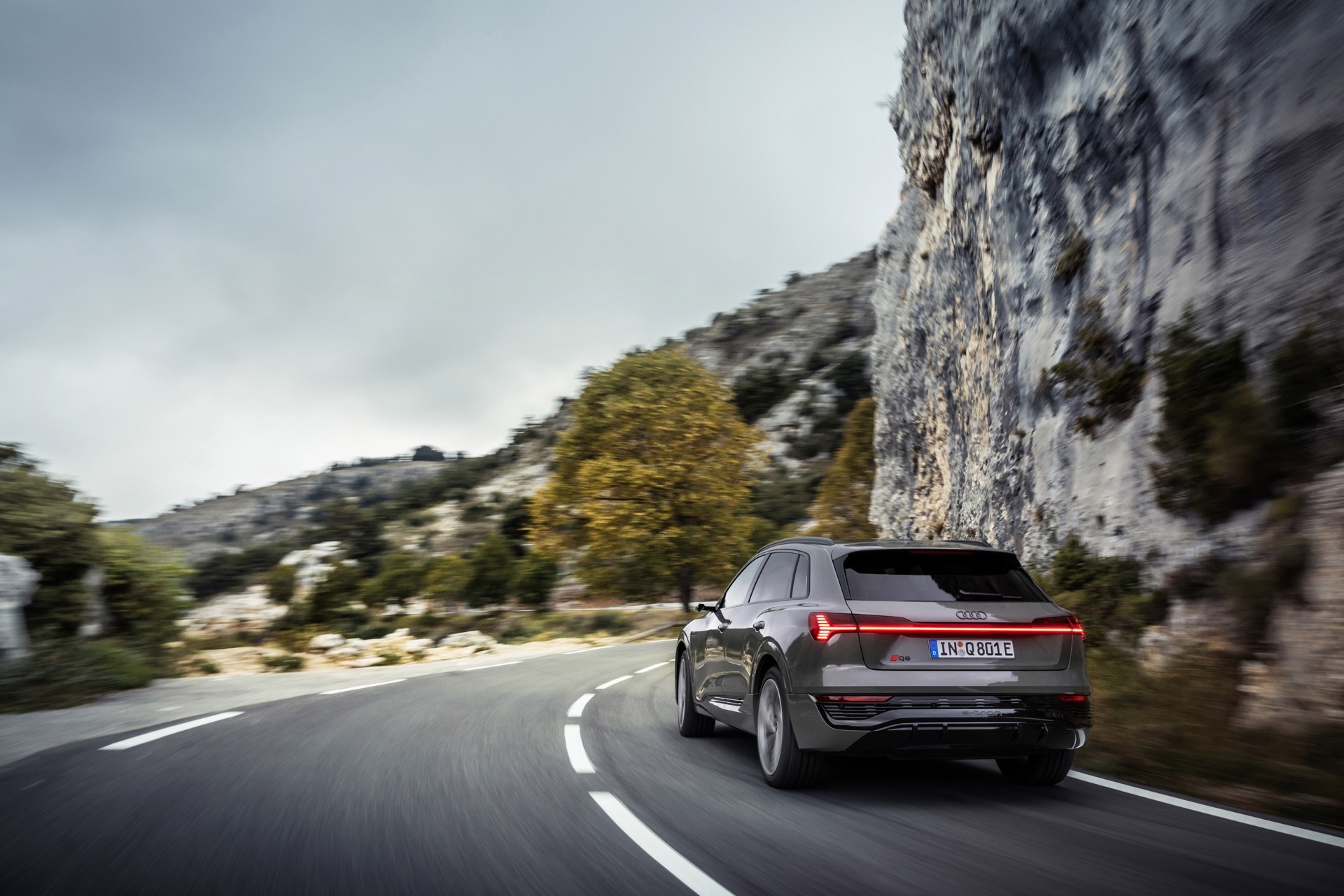 Audi Q8 e-tron capturado en plena ruta montañosa, destacando su diseño trasero y lateral.
