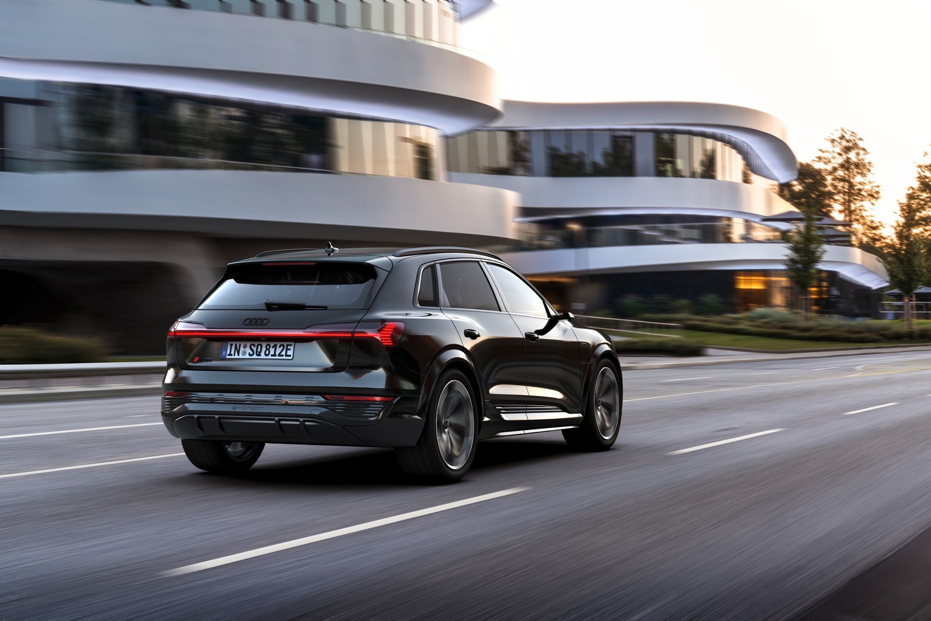 Vista dinámica de un Audi Q8 e-tron en entorno urbano, resaltando su diseño trasero y lateral.