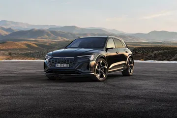 Vista dinámica del Audi Q8 e-tron destacando su imponente frontal y línea lateral.