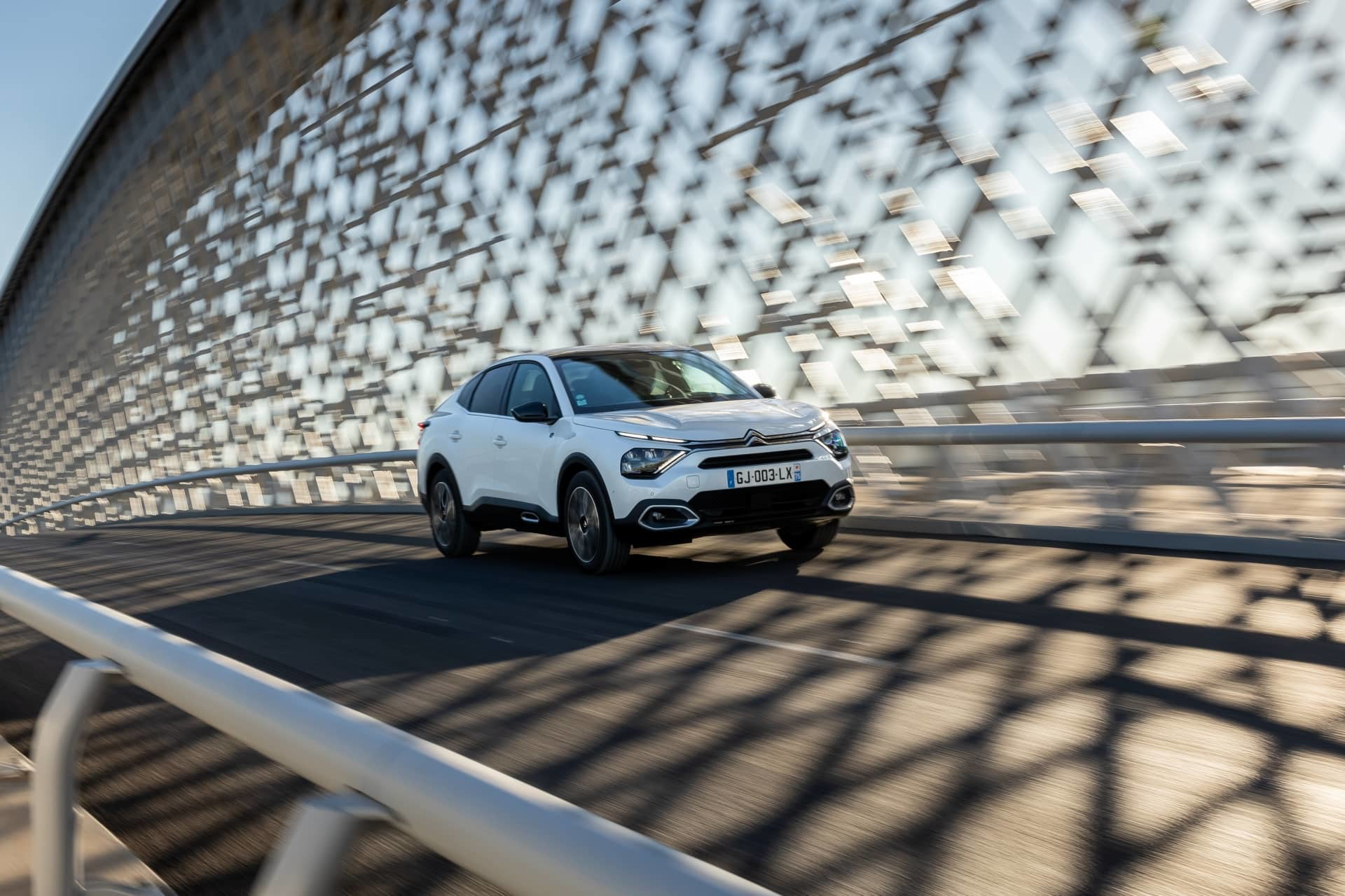 Citroën C4 X reflejado en superficie metálica, vista lateral.