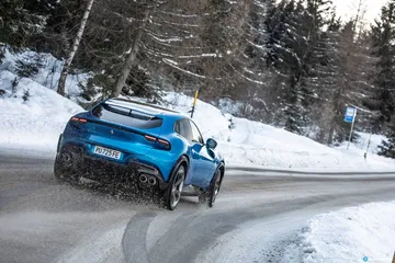 Ferrari Purosangue mostrando su línea lateral mientras rueda por carreteras nevadas.