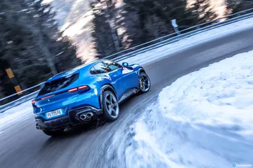 Vista lateral del Ferrari Purosangue en una carretera nevada.