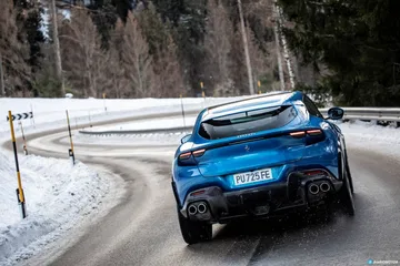 Ferrari Purosangue azul tomado desde angulo delantero-lateral en carretera nevada
