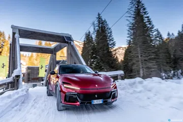Vista delantera y lateral del Ferrari Purosangue en un escenario nevado