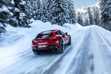 Vista trasera y lateral del Ferrari Purosangue en carretera nevada.