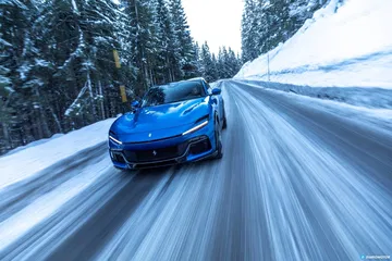 Ferrari Purosangue azul deslizándose sobre carretera nevada