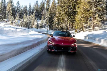 El Ferrari Purosangue deslizándose por una ruta nevada con elegancia y potencia.