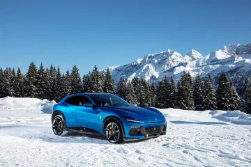 El Ferrari Purosangue posando con imponentes montañas al fondo.