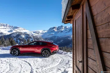 Vista lateral de un Ferrari Purosangue en un paisaje nevado, mostrando su perfil deportivo.