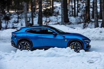 Vista lateral del Ferrari Purosangue en un paraje nevado, destacando su silueta.