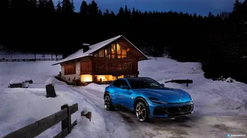 Vista lateral del Ferrari Purosangue iluminado bajo la noche invernal.