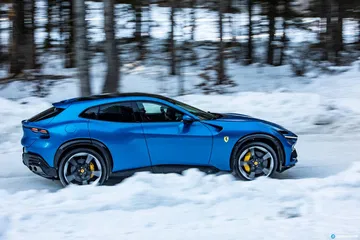 Vista lateral Ferrari Purosangue en paisaje invernal.