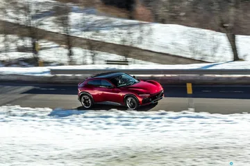 Vista lateral del Ferrari Purosangue en un entorno nevado, destacando su perfil deportivo.