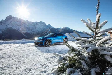 Vista lateral del Ferrari Purosangue sobre un paisaje nevado.