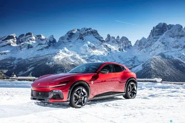 Vista lateral del Ferrari Purosangue sobre fondo de montañas nevadas.