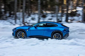 Vista lateral del Ferrari Purosangue sobre un manto de nieve.