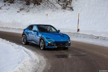Vista lateral del Ferrari Purosangue sobre una carretera nevada.