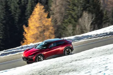 Vista lateral del Ferrari Purosangue desafiando terrenos nevados.