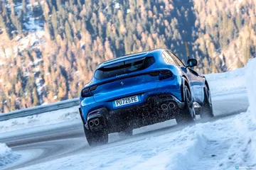 Vista lateral del Ferrari Purosangue en un entorno nevado, destacando su dinamismo.