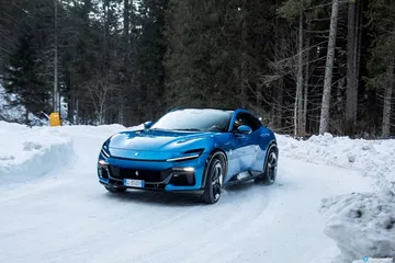 Vista delantera lateral del Ferrari Purosangue azul sobre la nieve.