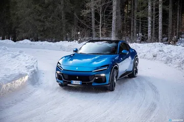 Vista delantera y lateral del Ferrari Purosangue sobre un manto de nieve.