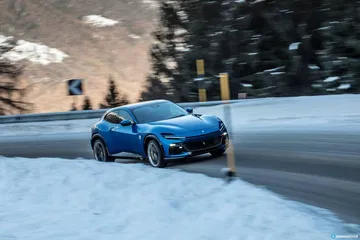 Vista lateral del Ferrari Purosangue sobre la nieve, destacando su dinámica silueta.