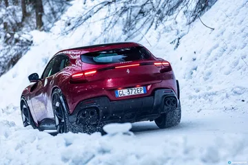 Vista trasera y lateral del Ferrari Purosangue en condiciones de nieve.