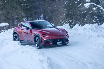 Vista lateral del Ferrari Purosangue sobre un paisaje nevado.