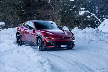 Vista delantera y lateral del Ferrari Purosangue sobre un paisaje nevado.