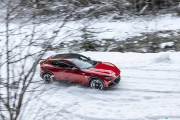 Vista lateral del Ferrari Purosangue deslizándose sobre un manto de nieve.
