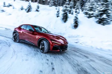 Vista lateral del Ferrari Purosangue en acción sobre superficie nevada.