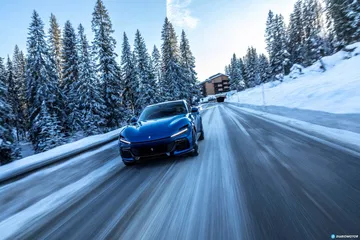 Vista lateral del Ferrari Purosangue deslizándose por una carretera nevada.