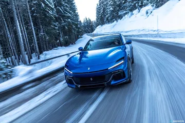Ferrari Purosangue avanzando por carretera nevada, vista frontal y lateral.