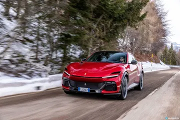 Vista lateral del Ferrari Purosangue avanzando en carretera nevada. Vista lateral del Ferrari Purosangue avanzando en carretera nevada.