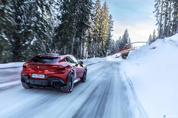 Vista trasera y lateral del Ferrari Purosangue en una carretera nevada.