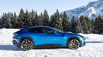 Vista lateral del Ferrari Purosangue con imponentes montañas al fondo.