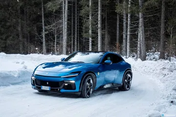 Vista lateral del Ferrari Purosangue sobre un manto de nieve.