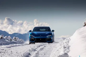 Vista trasera del Ferrari Purosangue destacando su diseño mientras maneja sobre nieve.