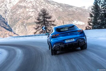 Vista dinámica del Ferrari Purosangue sobre paisaje nevado.