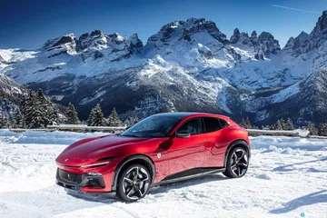 Vista lateral del Ferrari Purosangue sobre fondo montañoso nevado.