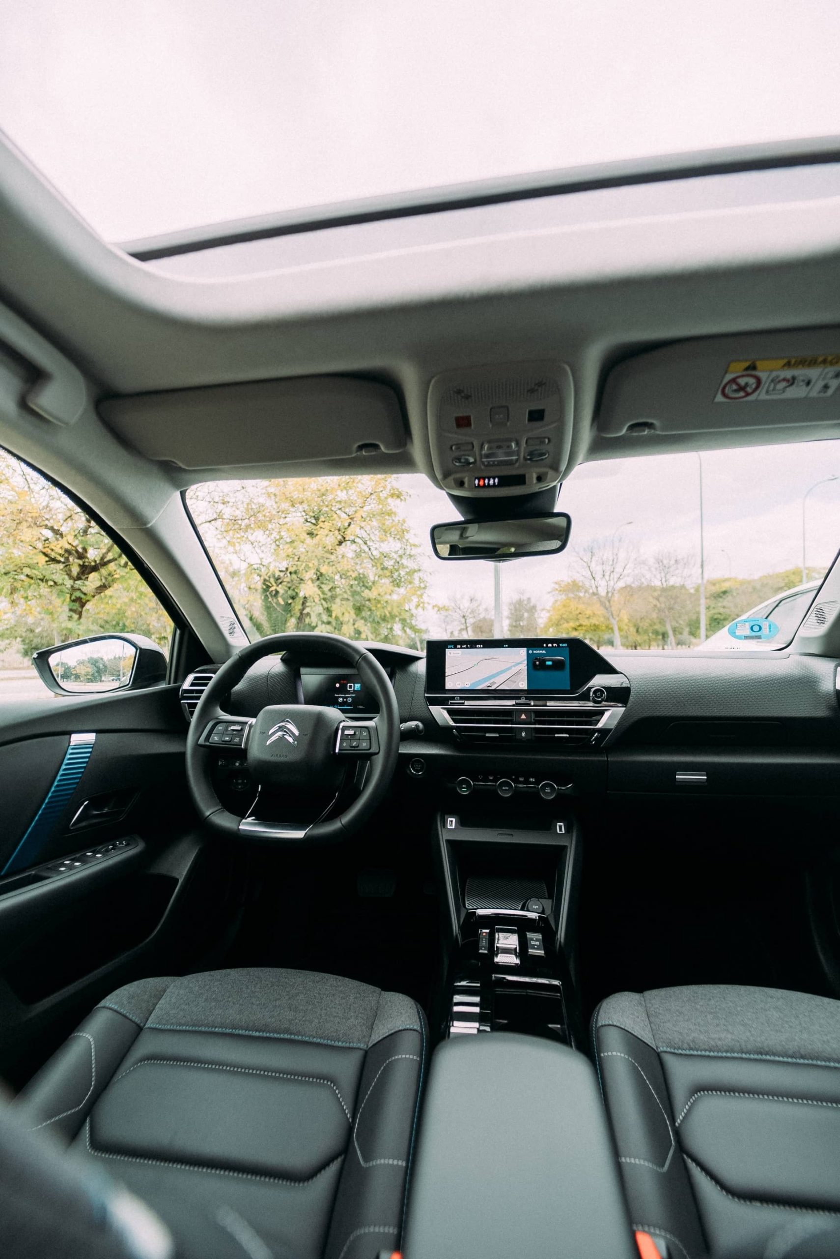 Elegante cabina del Citroën C4 X con amplio techo panorámico y diseño contemporáneo.