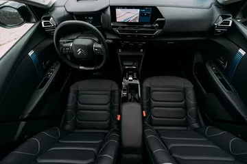 Vista frontal de la cabina del conductor en el Citroën C4 X, enfocando asientos y consola central.