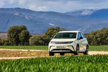 Vista del BYD Dolphin en un entorno natural, destacando su línea lateral y frontal.