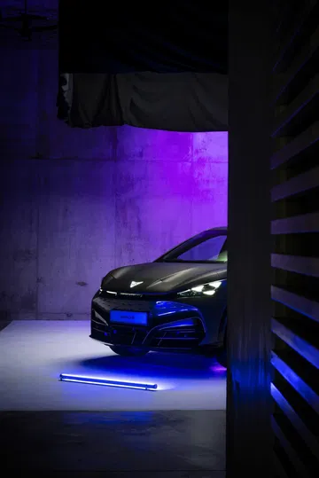 Vista parcial delantera del CUPRA Tavascan iluminada en azul.