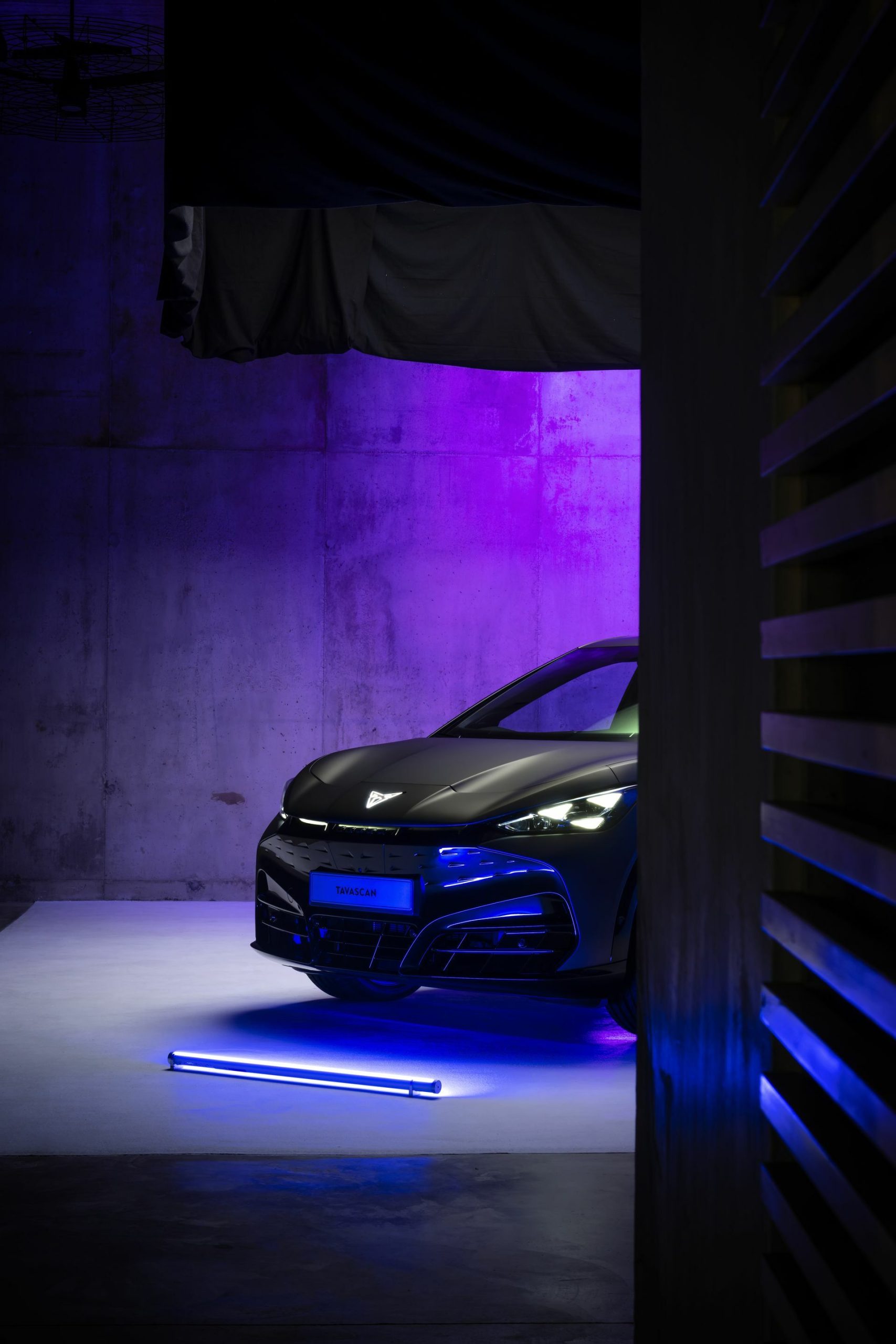 Vista parcial delantera del CUPRA Tavascan iluminada en azul.