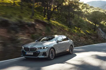 BMW Serie 5 en conducción por curvas montañosas, vista frontal-lateral.