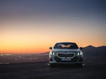 Vista frontal y trasera del BMW Serie 5 al atardecer, destacando su diseño elegante.
