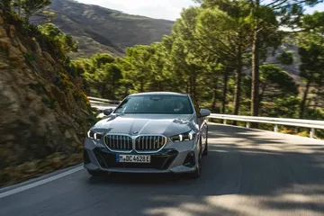Vista frontal y lateral de un BMW Serie 5 en carretera de montaña